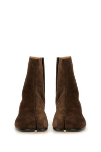 Maison Margiela men’s tabi boot in brown suede with split-toe design and black rubber soles shown from the back side