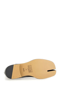 Maison Margiela men’s tabi Chelsea boot in black and tan leather with split toe and brand label on sole visible from back