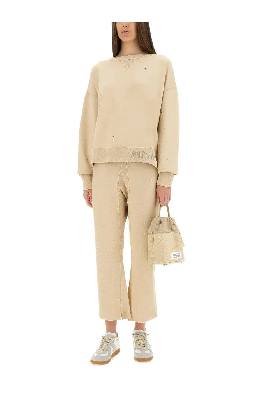 Beige canvas bucket bag with drawstring top and small white label paired with maison margiela unisex white cotton pants
