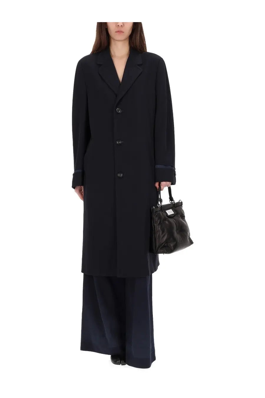 Black oversized coat with structured collar and button closure paired with maison margiela women’s blue chino pants