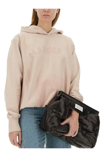 Black quilted cotton clutch with a minimalist white label on the strap paired with Maison Margiela blue sweatshirt