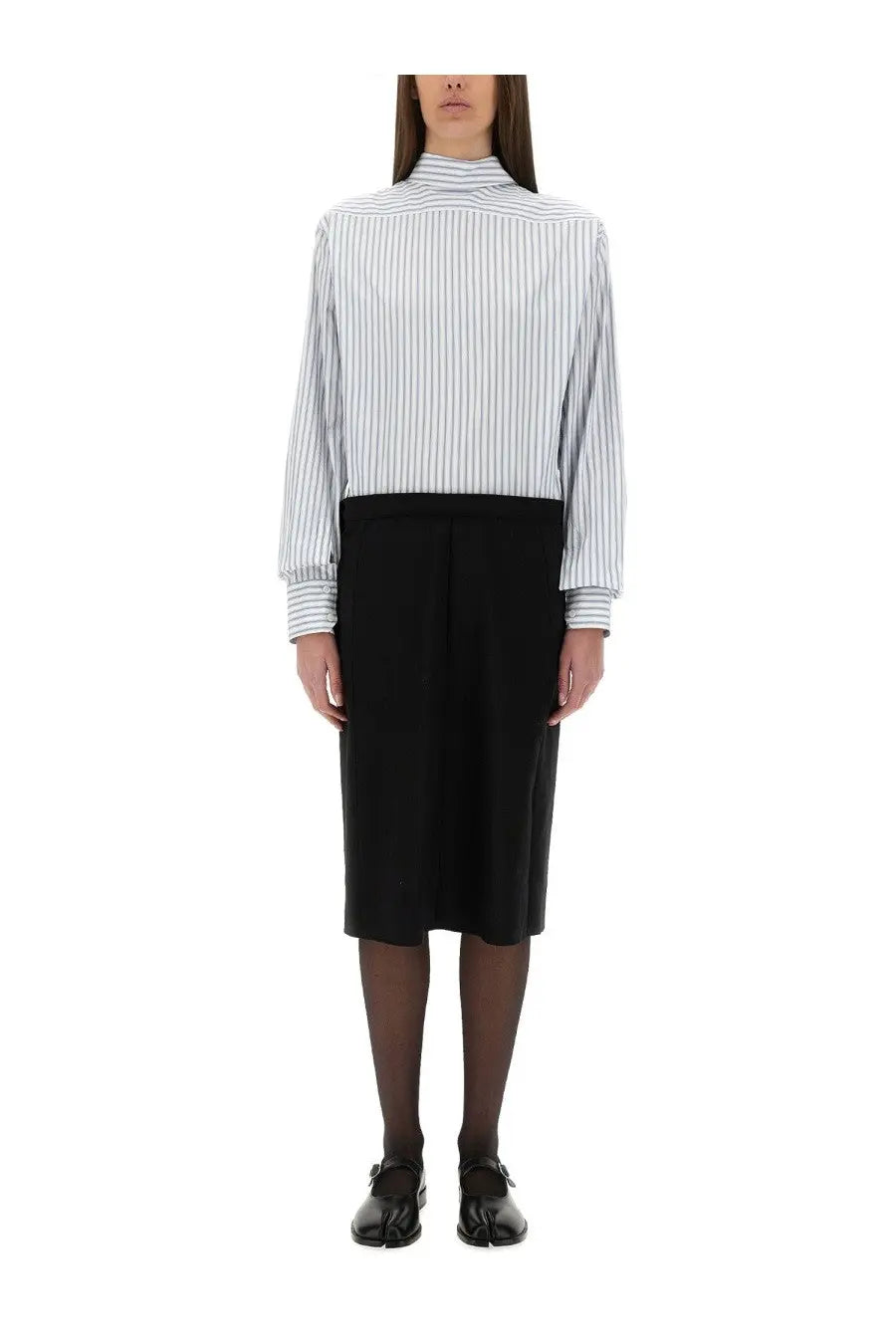 A woman wears a maison margiela women’s inverted striped dress shirt with white and navy vertical stripes paired with a black midi skirt