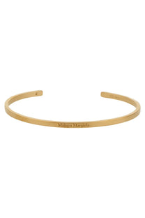 Gold-toned maison margiela women’s open cuff bracelet with minimalist engraved branding on polished metal surface