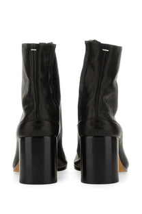 Back view of Maison Margiela women’s Stivale Tabi black leather ankle boots with glossy block heel and silver zipper detail