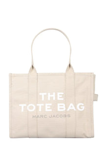 Beige canvas tote bag with white the tote bag lettering and smaller gray marc jacobs text below by Marc Jacobs