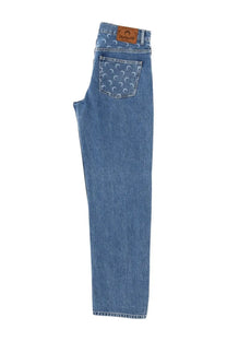 Back view of marine serre men’s moon waxed jeans blue in blue denim with crescent moon pattern and brown leather patch