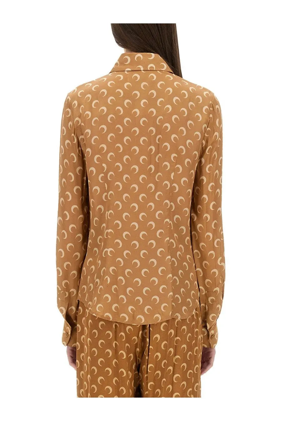 A woman wears a caramel-colored marine serre women’s moon satin shirt with cream crescent moon pattern and long sleeves