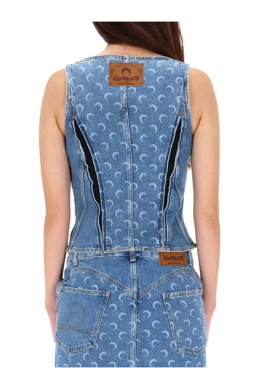 Back view of marine serre women’s blue denim sleeveless jumpsuit with white crescent moon pattern and black zipper accents