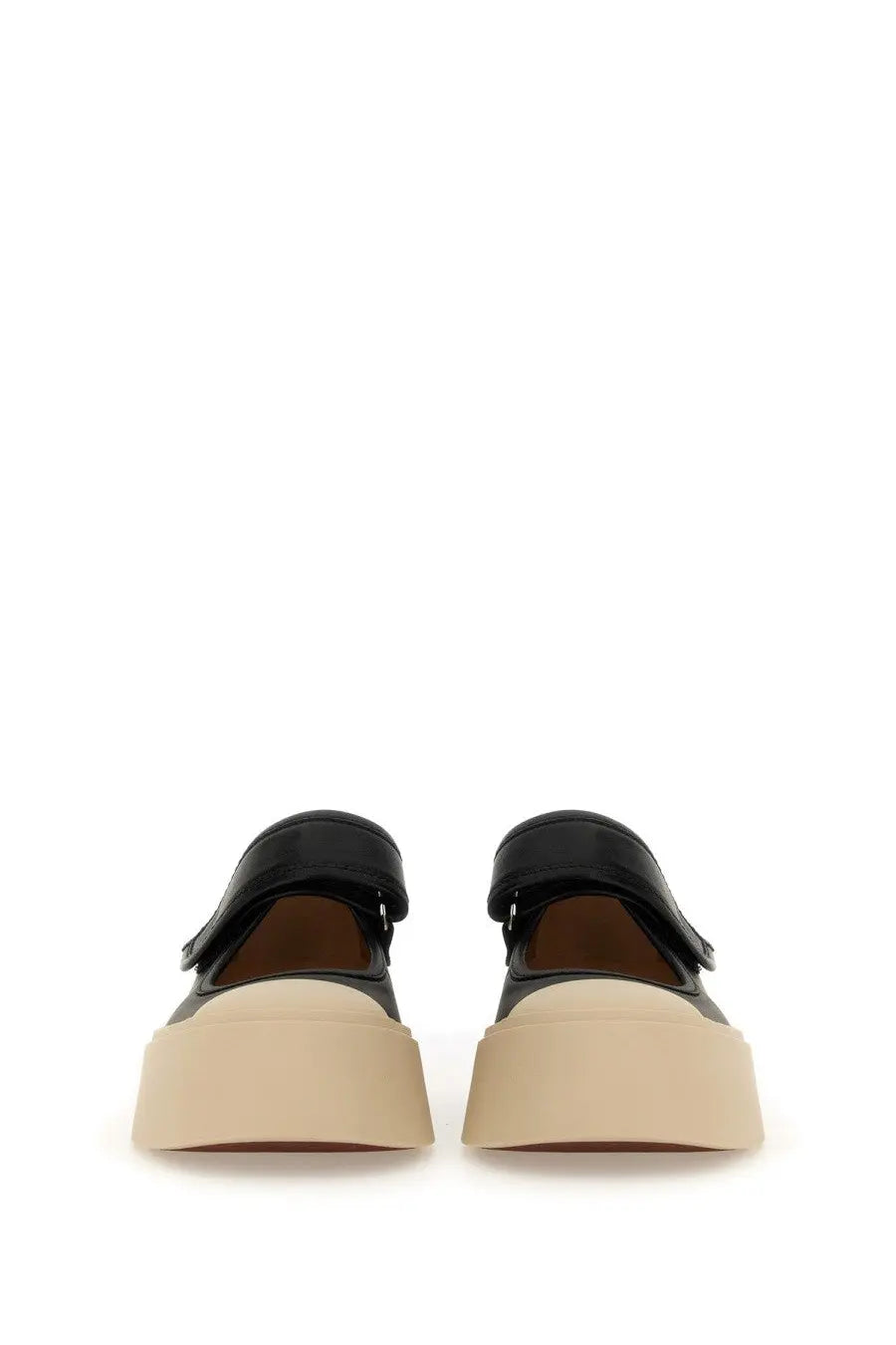 Black leather platform shoes with a beige rubber sole and velcro strap closure.