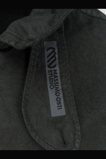 Dark gray textured fabric collar with silver massimo osti studio label on men’s nylon jacket darkshadow