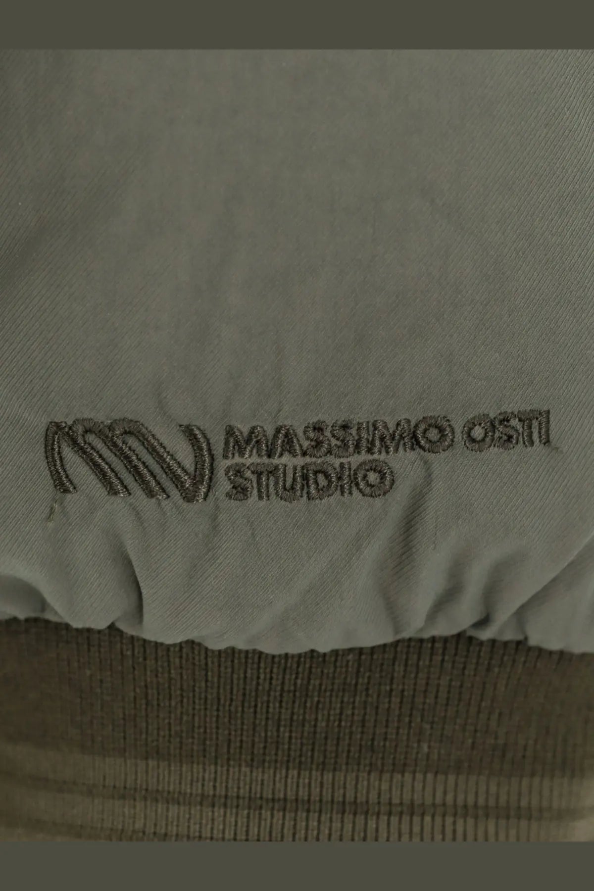 Light gray fabric with subtle embroidered massimo osti studio logo on the back of men’s padded nylon jacket brown