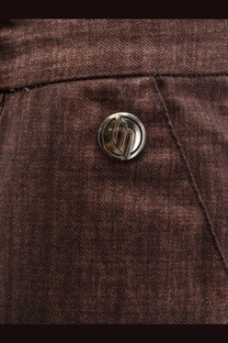 Silver circular button with stylized logo on dark brown denim fabric of massimo osti men’s wool gum trousers brown