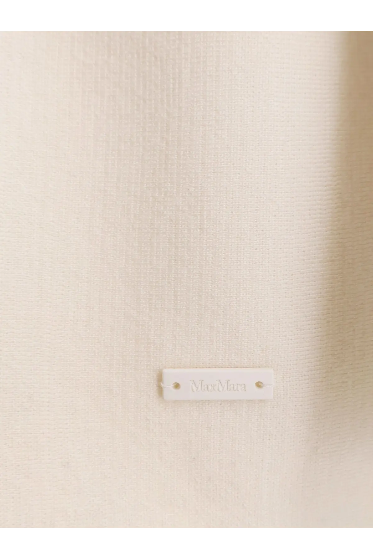 A minimalist white rectangular label embossed with moonara on a max mara women’s aster virgin wool cardigan white