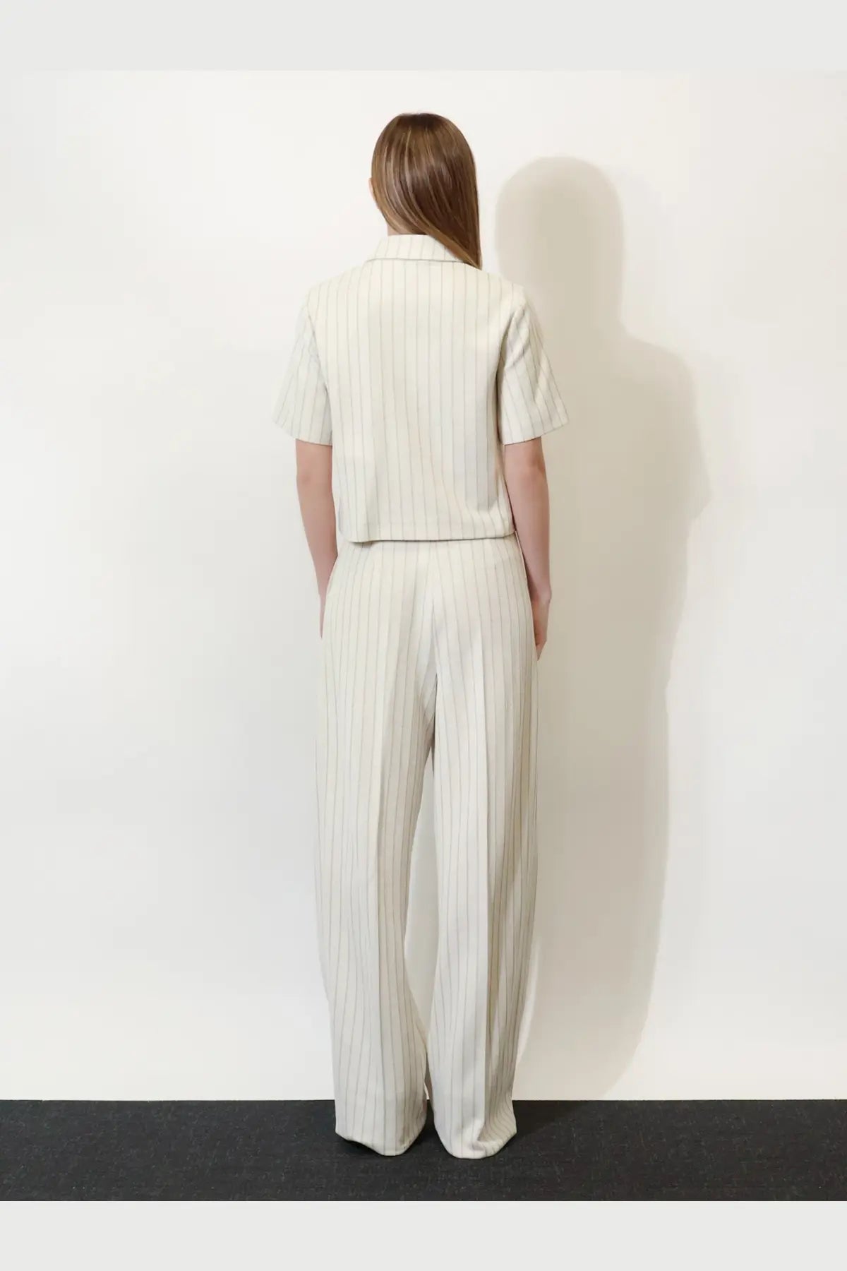 A woman wears Max Mara women’s Mxmosso white cotton wide-leg trousers with a cream striped short-sleeved shirt