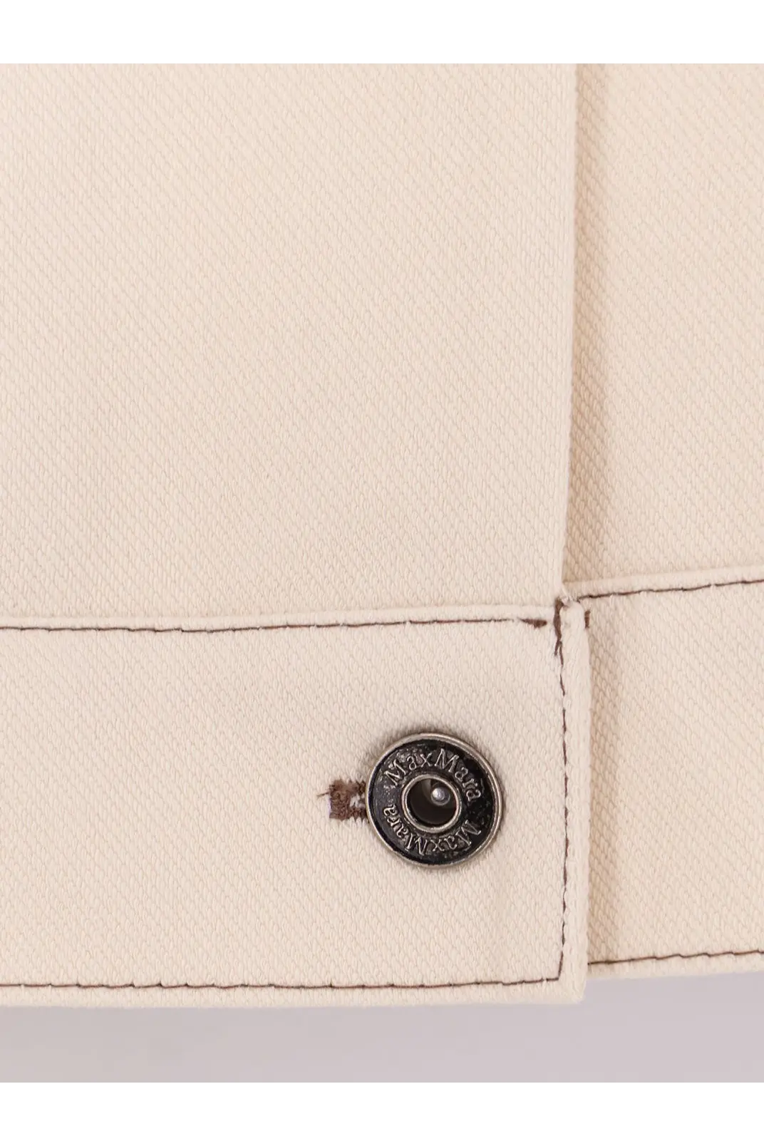 A circular dark metal button with engraved text on a cream fabric cuff of max mara womens mxpnettare jersey jacket white