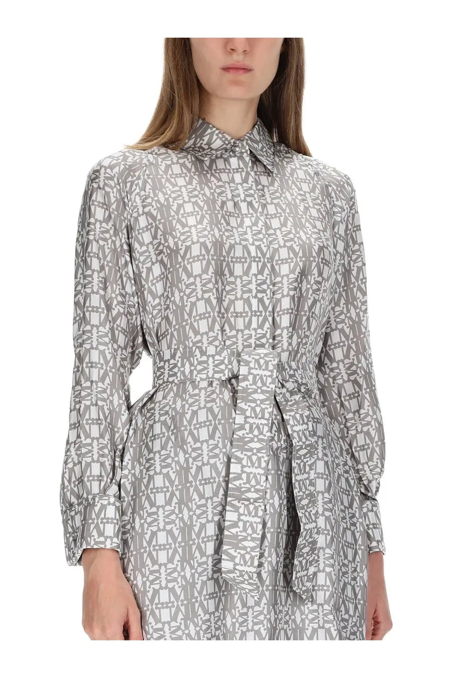 A woman wearing a max mara women’s beige printed silk chemisier dress with gray and white geometric pattern and tied waist belt