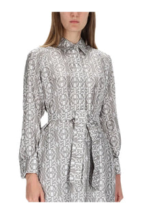 A woman wearing a max mara women’s beige printed silk chemisier dress with gray and white geometric pattern and tied waist belt