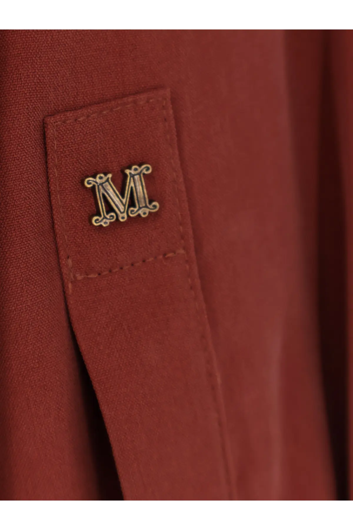 A gold-toned ornate m emblem pin on the rust-colored silk pocket of max mara womens siamese silk shirt brown