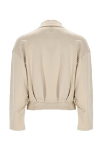 Beige faux leather cropped jacket with structured collar and subtle back pleats shown from the back side