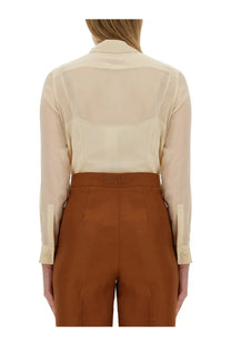 A beige semi-sheer silk blouse with classic collar and buttoned cuffs paired with brown high-waisted trousers