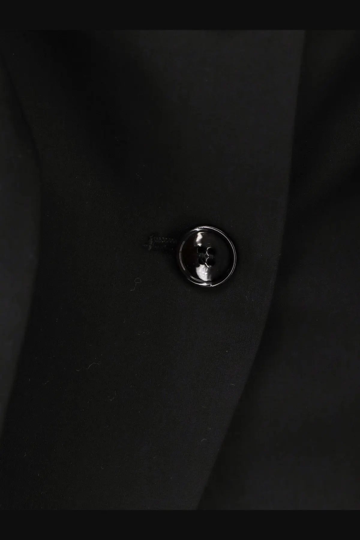 A sleek glossy black button with metallic sheen on max mara women’s veruska virgin wool top black fabric