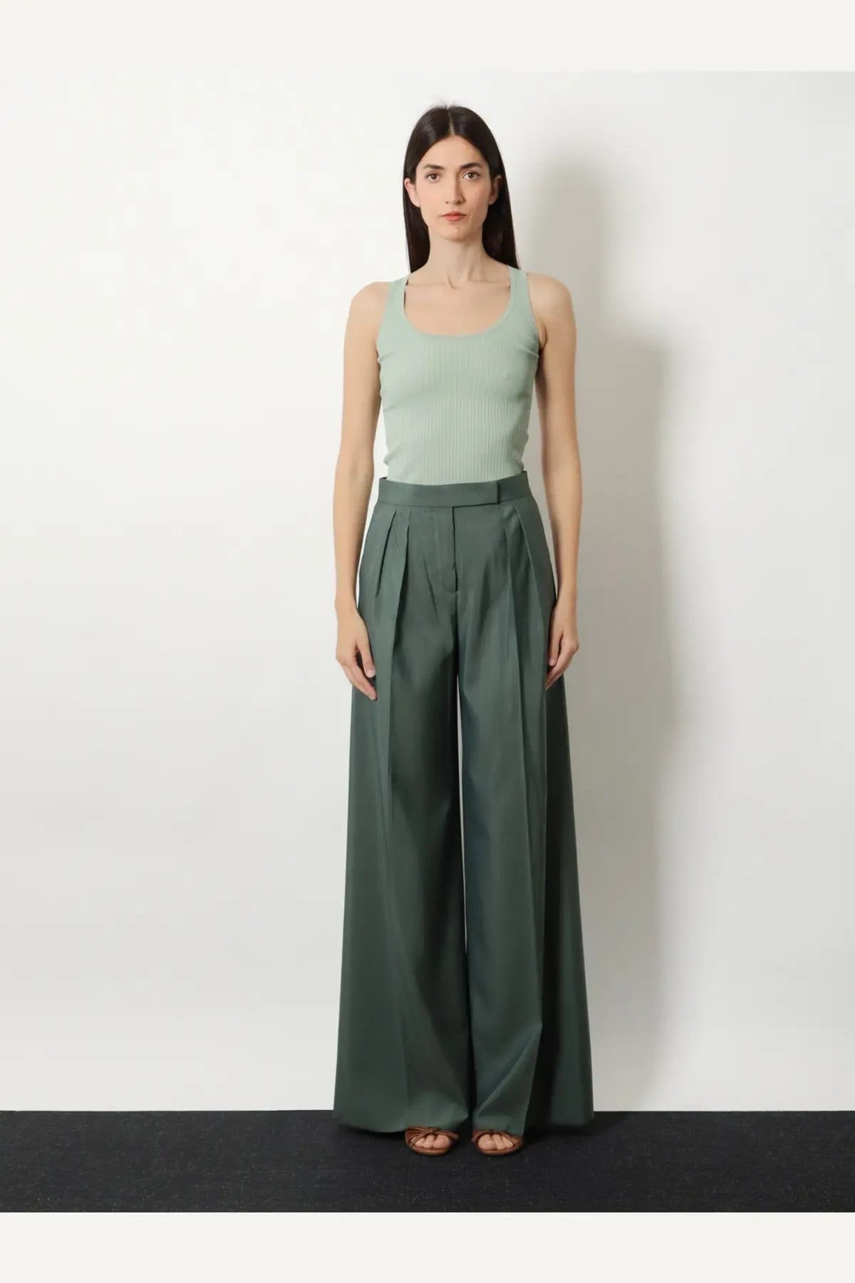 A pair of wide-leg high-waisted trousers in deep olive green viscose blend fabric with waist pleats