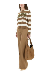 Tan leather shoulder bag with structured slouchy silhouette and gold tone hardware paired with Max Mara wide pants in fernet beige