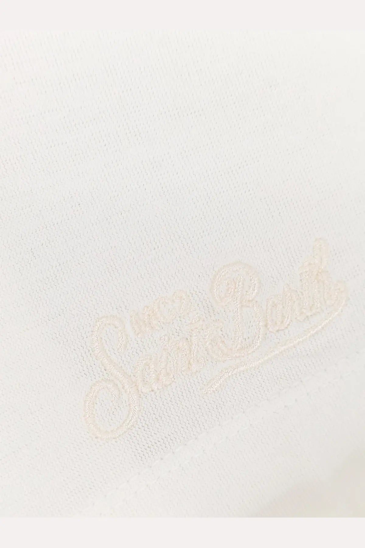Cream-colored sneaker bunk logo embroidered in cursive on soft white fabric of mc2 saint barth men’s orson cotton shirt