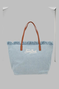 Light blue denim tote bag with brown leather handles and frayed top edge embroidered with saint barth script