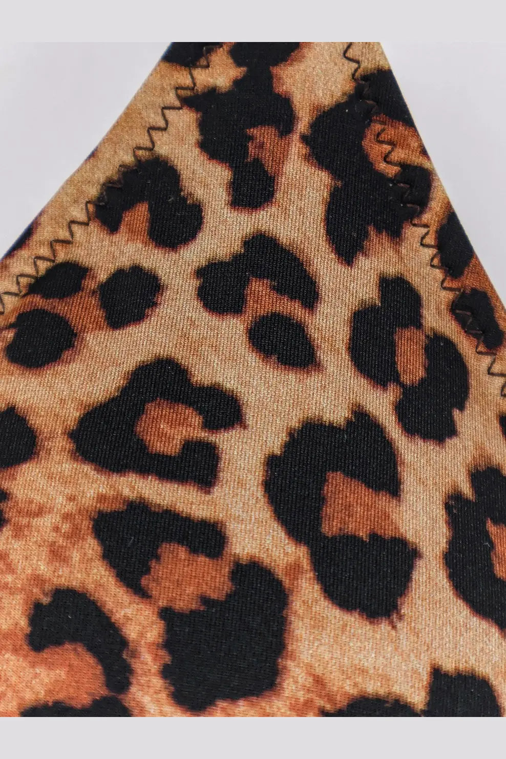 Close-up of mc2 saint barth women’s leah nylon bikini top in beige leopard print with bold black spots and stitched edge