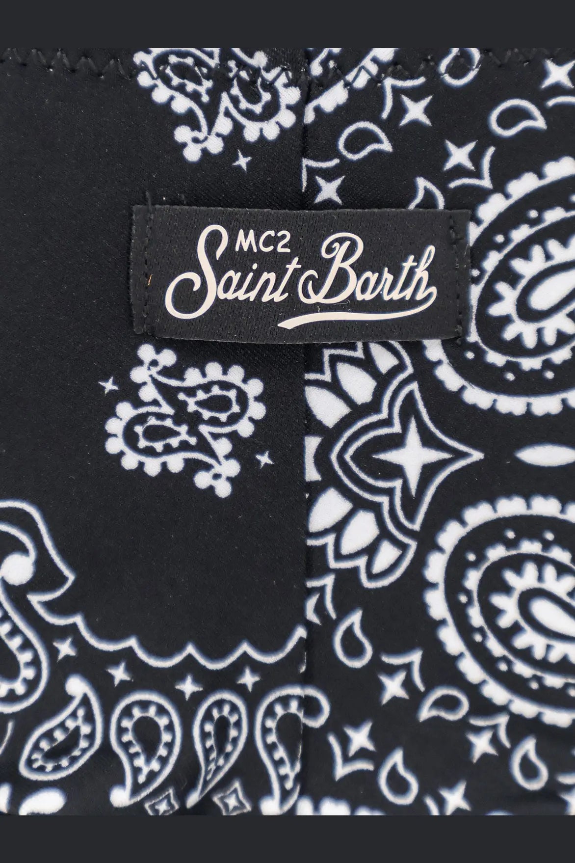 Black fabric with white paisley and star pattern and mc2 saint barth label on women’s stretch nylon bikini bottoms
