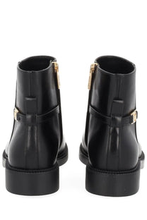 Black patent leather ankle boots by Michael Kors with gold-tone zippers and buckle details for women