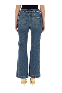 Back view of michael kors women’s blue denim flare fit jeans with gold chain belt and embroidered back pocket logo
