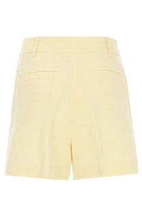 Back view of michael kors women’s cream-colored tailored shorts in lino yellow with structured waistband and two back pockets