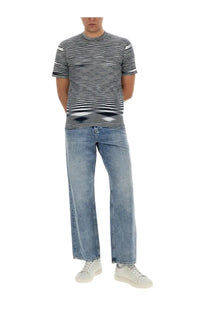 A man wearing a Missoni men’s cotton shirt in blue with black and white horizontal stripes paired with light blue denim jeans