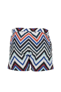 Missoni men’s swimsuit featuring vibrant zigzag-patterned swim trunks in bold red, blue, black, and white