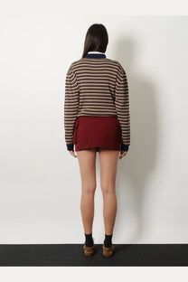 A woman wears a brown and beige striped cotton rugby sweater with navy trim paired with a red Miu Miu cotton mini skirt