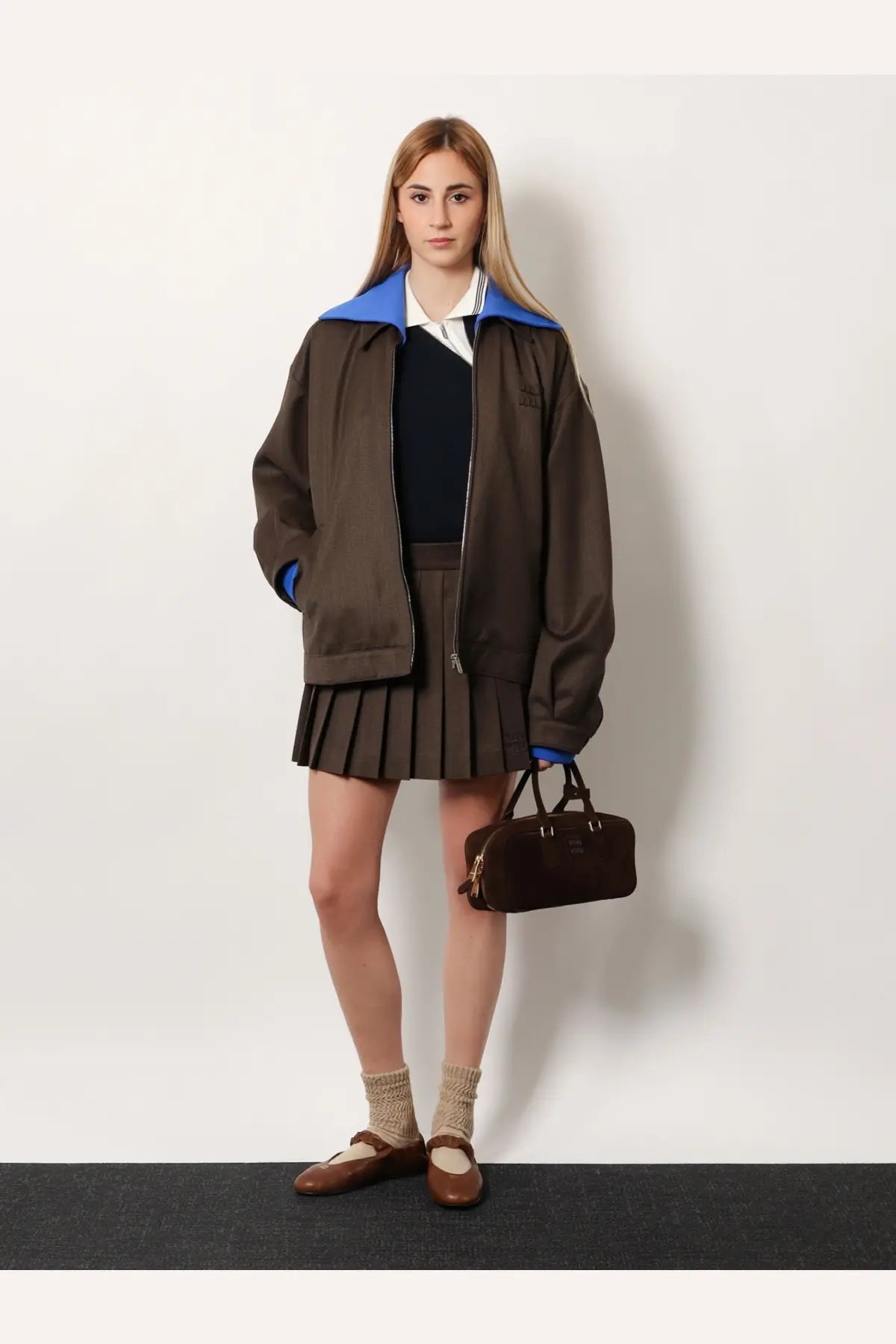 Brown suede handbag with black leather handles and small metallic logo paired with miu miu women’s blue cotton polo shirt