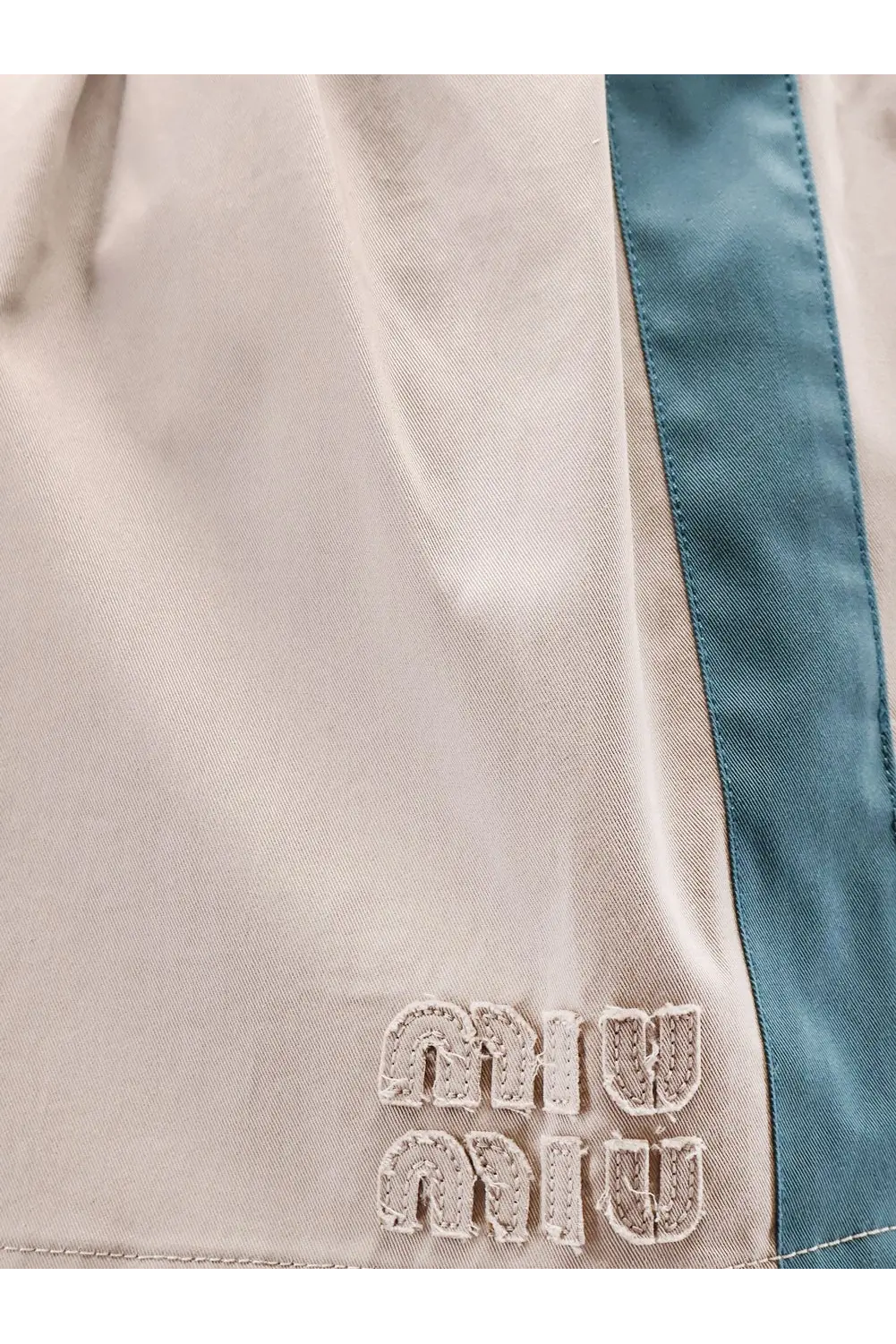 Beige miu miu shorts with teal side stripe and embroidered logo paired with a green old twill mini skirt