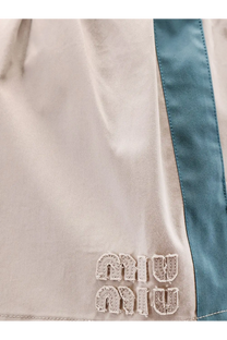Beige miu miu shorts with teal side stripe and embroidered logo paired with a green old twill mini skirt