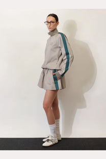 A gray athletic tracksuit set with teal stripes and high collar featuring subtle brand embroidery and matching skirt