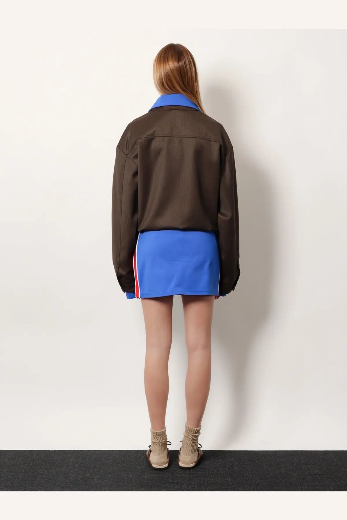 Brown bomber jacket with blue collar and cuffs and red and white stripes paired with miu miu blue recycled mini skirt