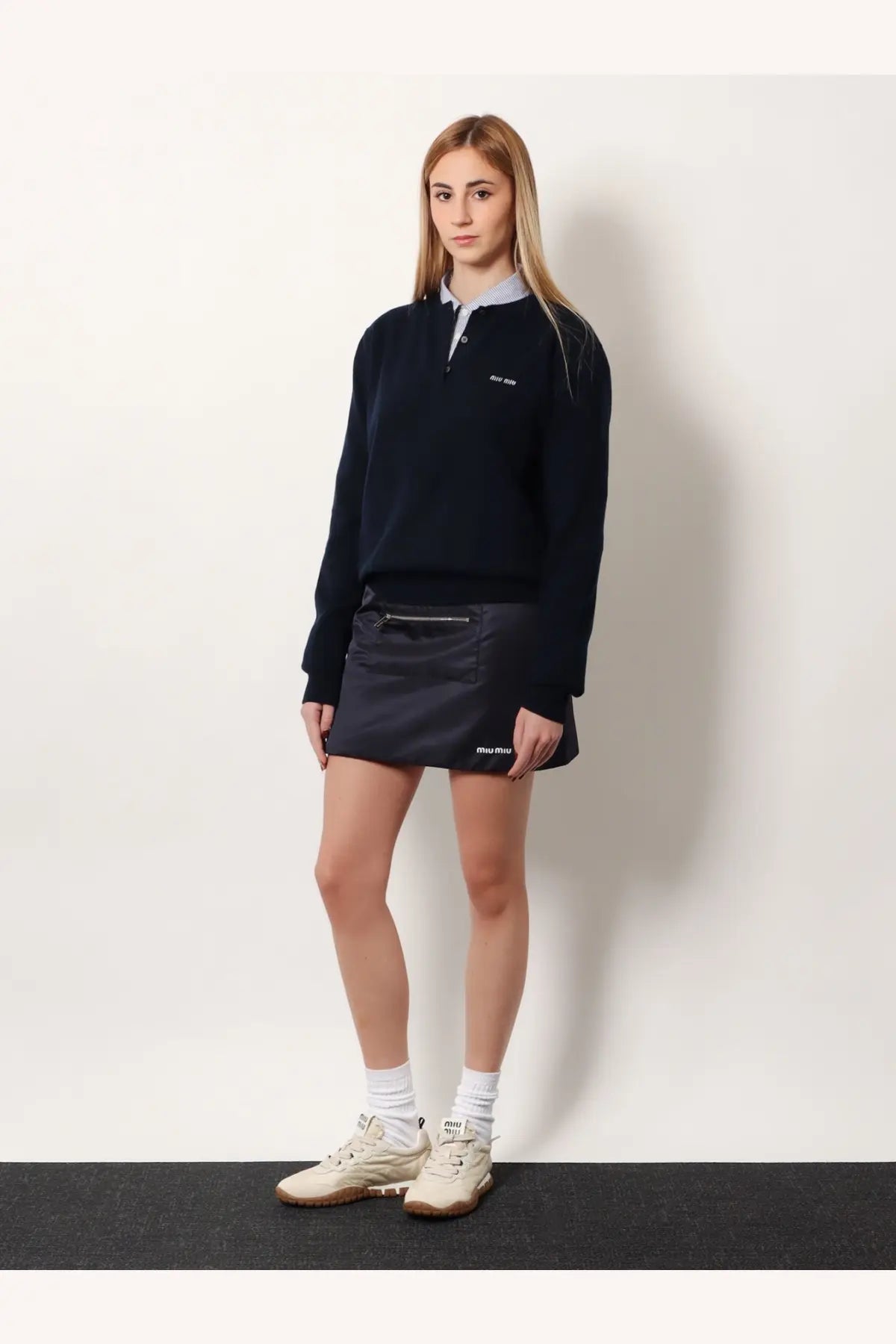 Navy blue miu miu sweater with subtle embroidered logo and ribbed cuffs paired with recycled material mini skirt blue