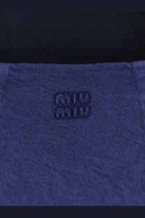 Deep blue denim fabric with subtle texture and embossed miu miu logo on miu miu women’s short denim dress inchiostro