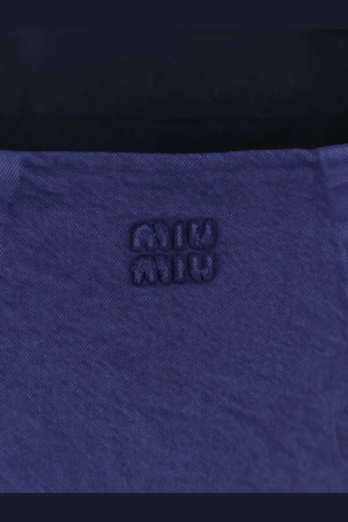 Deep blue denim fabric with textured weave and embossed miu miu logo on miu miu women’s short denim dress inchiostro
