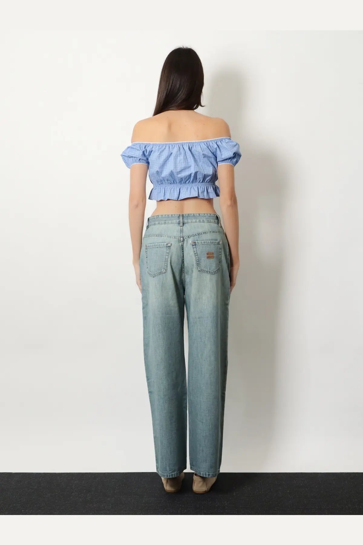 Light-wash denim jeans with relaxed wide-leg cut and subtle distressing paired with miu miu women’s blue striped cotton top
