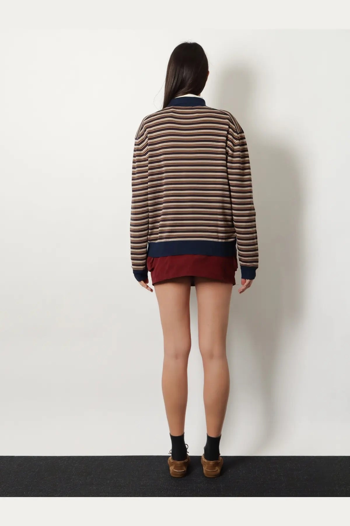 A woman wearing a miu miu women’s virgin wool polo shirt white with a long-sleeved striped sweater and maroon hemline
