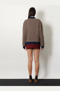 A woman wearing a miu miu women’s virgin wool polo shirt white with a long-sleeved striped sweater and maroon hemline