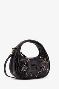 A black leather miu miu handbag with sparkling crystal embellishments and a gold-tone logo front detail