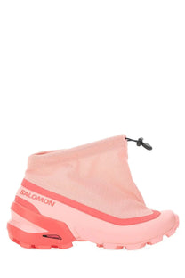 Pink salomon hiking boot with mesh upper and coral accents on midsole and outsole next to mm6 maison margiela cross low sneaker blue